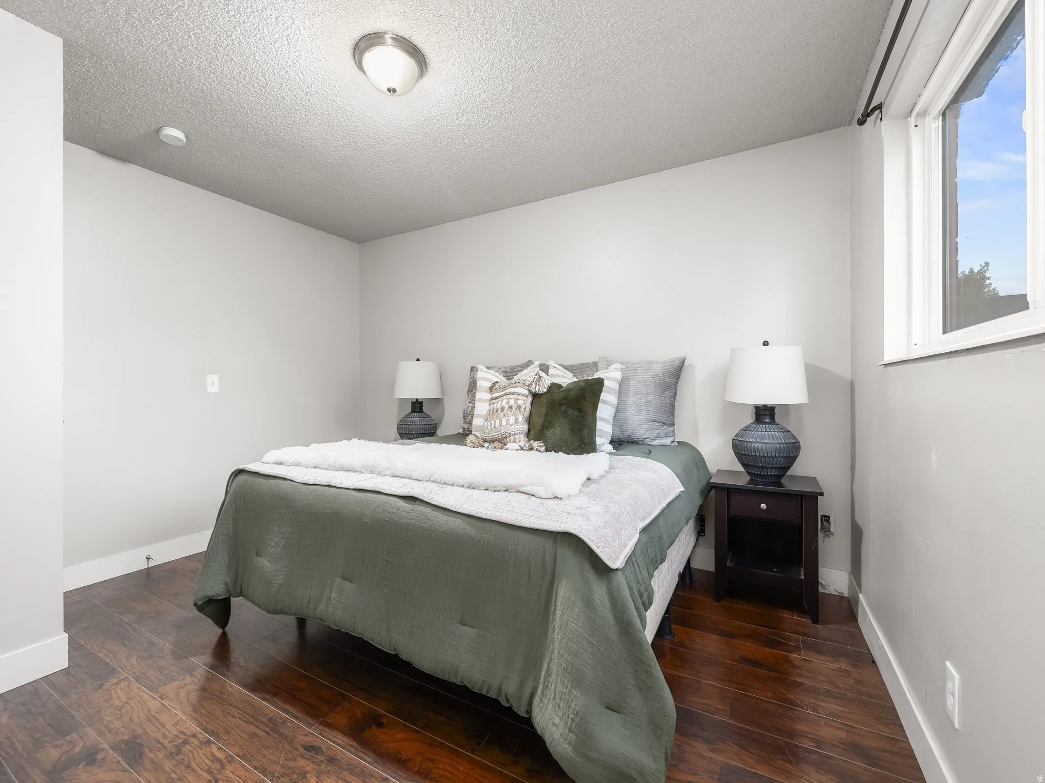 Bedroom featuring rich wood-finish flooring, a contemporary window, and a ceiling-mounted light fixture