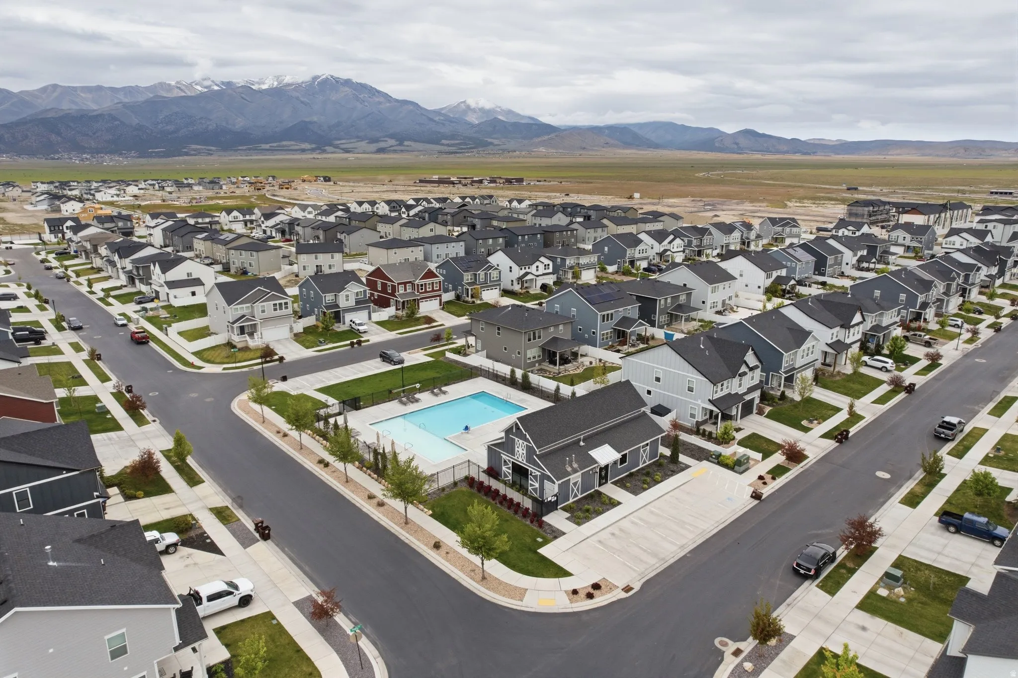 Community featuring a central swimming pool with surrounding fencing, paved streets, and a variety of detached homes