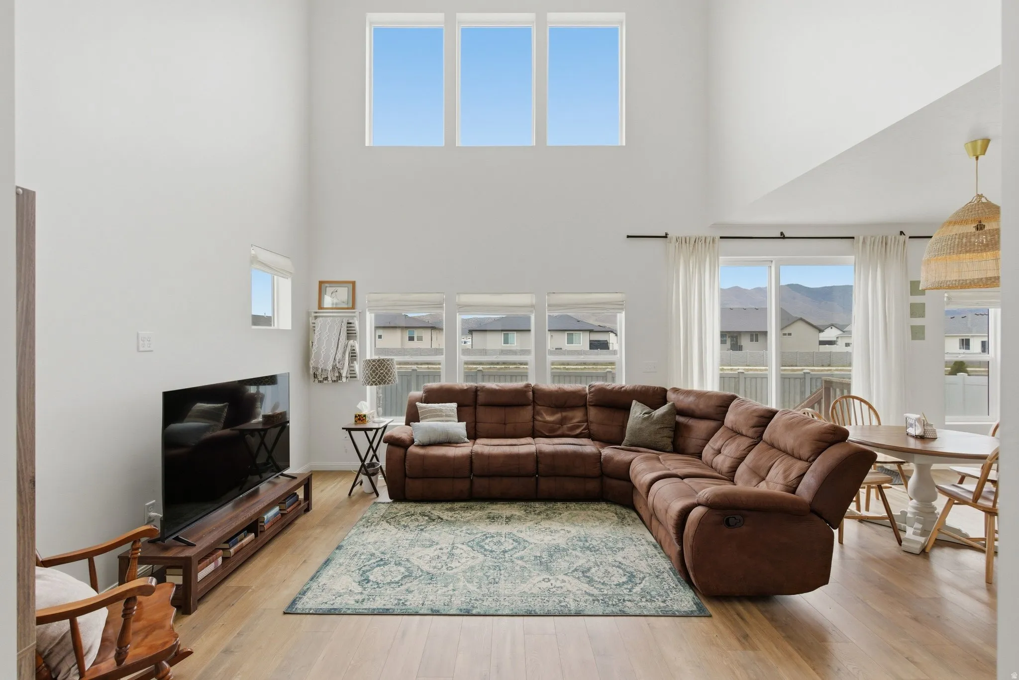 High ceilings featuring upper-level windows, wood-finish flooring, and sliding glass doors