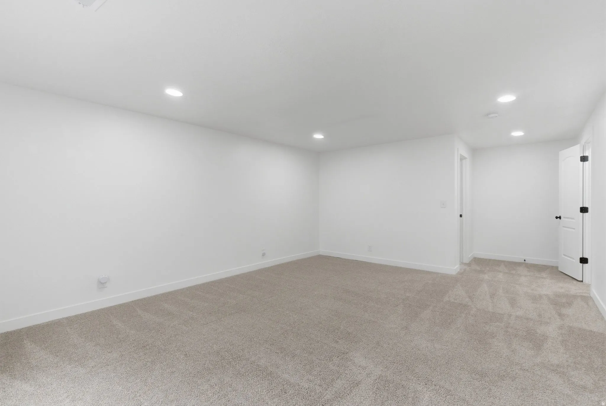 Spacious room featuring neutral carpeting, white walls, recessed ceiling lighting, and white trim