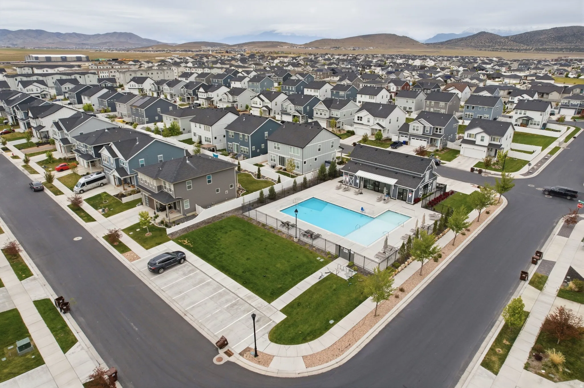 Community swimming pool with surrounding patio, adjacent lawn, and a nearby building