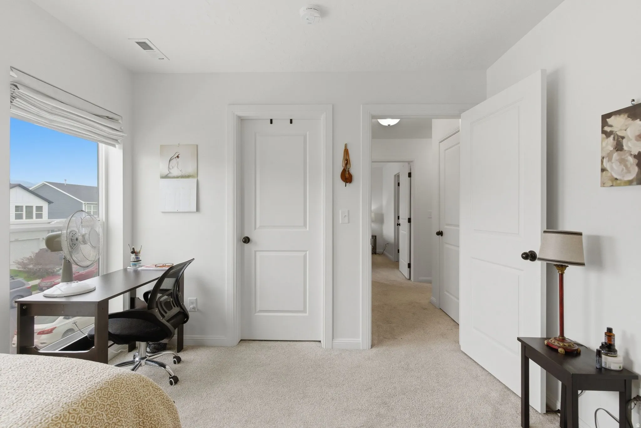 Carpeted interior room featuring white panel doors, white trim, and a window with a roller shade