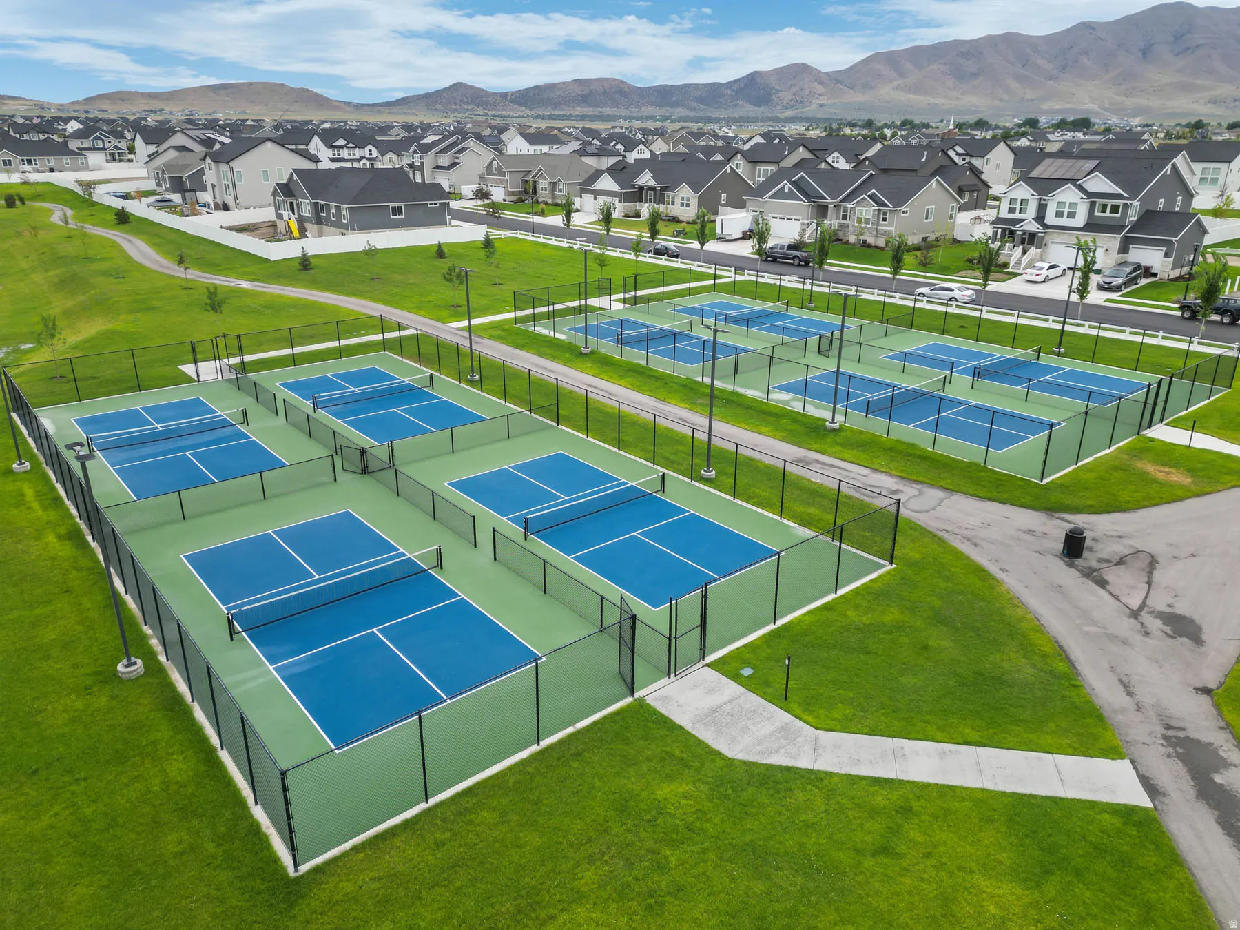 Six fenced pickleball courts with blue and green surfaces