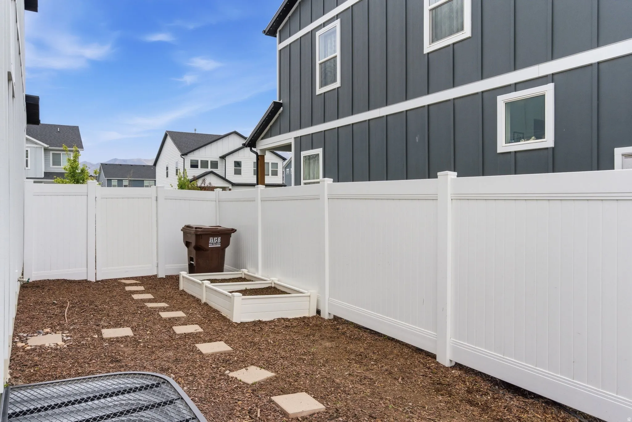 Private fenced yard featuring a stepping stone path and a raised garden bed