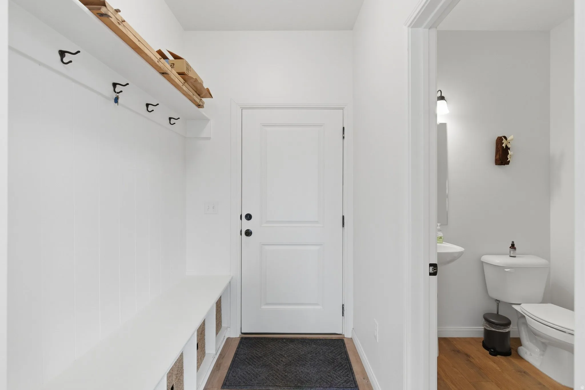 Entryway featuring built-in bench seating with storage, coat hooks, and a high shelf