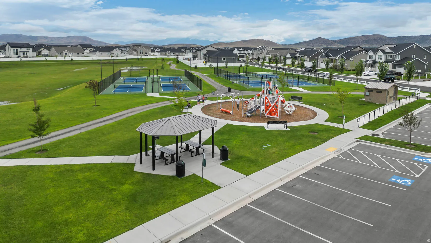 Community park area featuring an expansive playground, multiple tennis courts, a covered picnic gazebo, and paved walking paths
