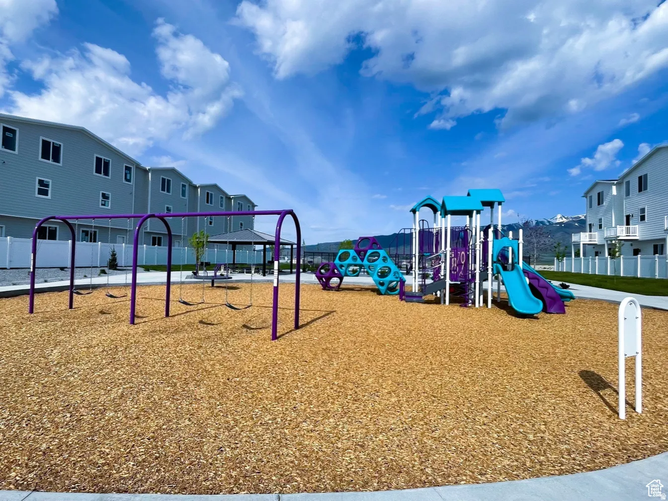 Community playground featuring a swing set, multi-level play structure with slides, and wood chip surfacing