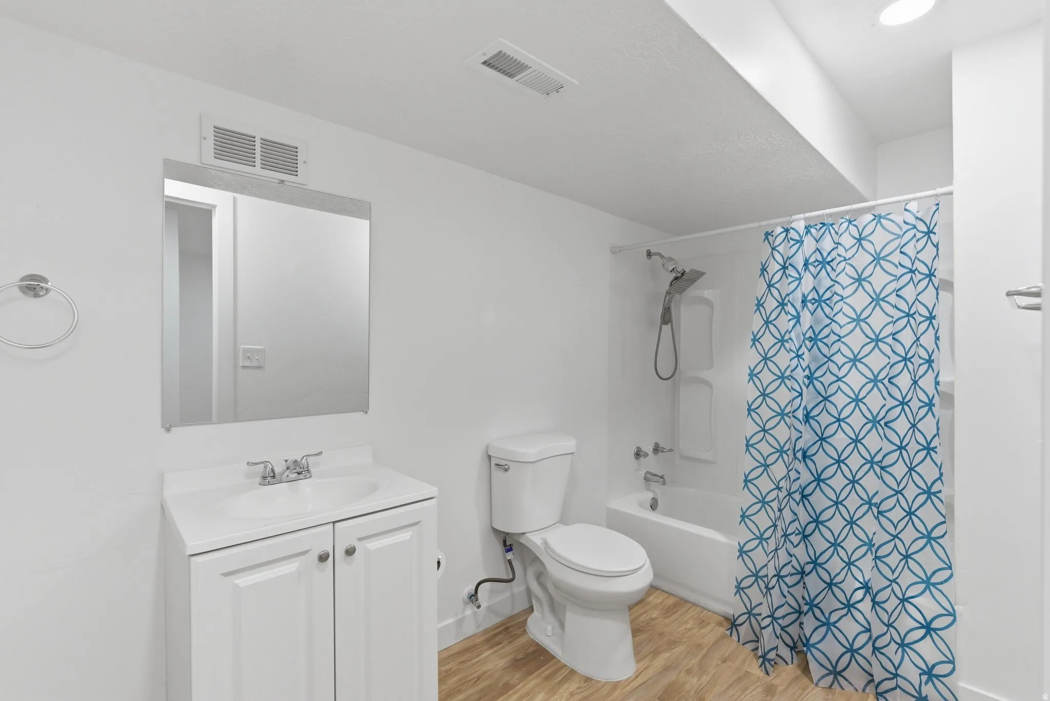 Bathroom featuring a white vanity with cabinet storage, a toilet, and a combined shower-tub unit