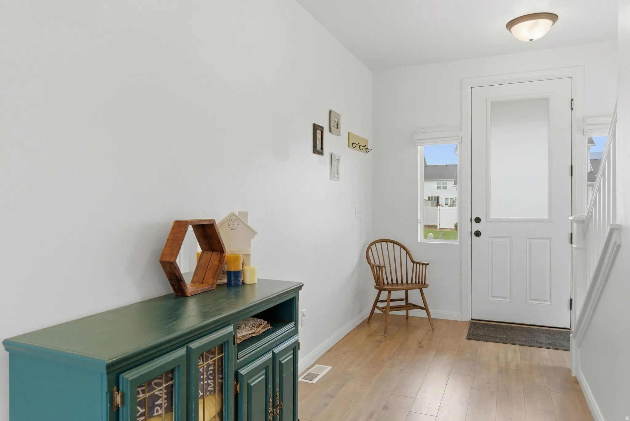 Entryway featuring wood-finish flooring, white walls, and a white paneled door with an upper glass insert