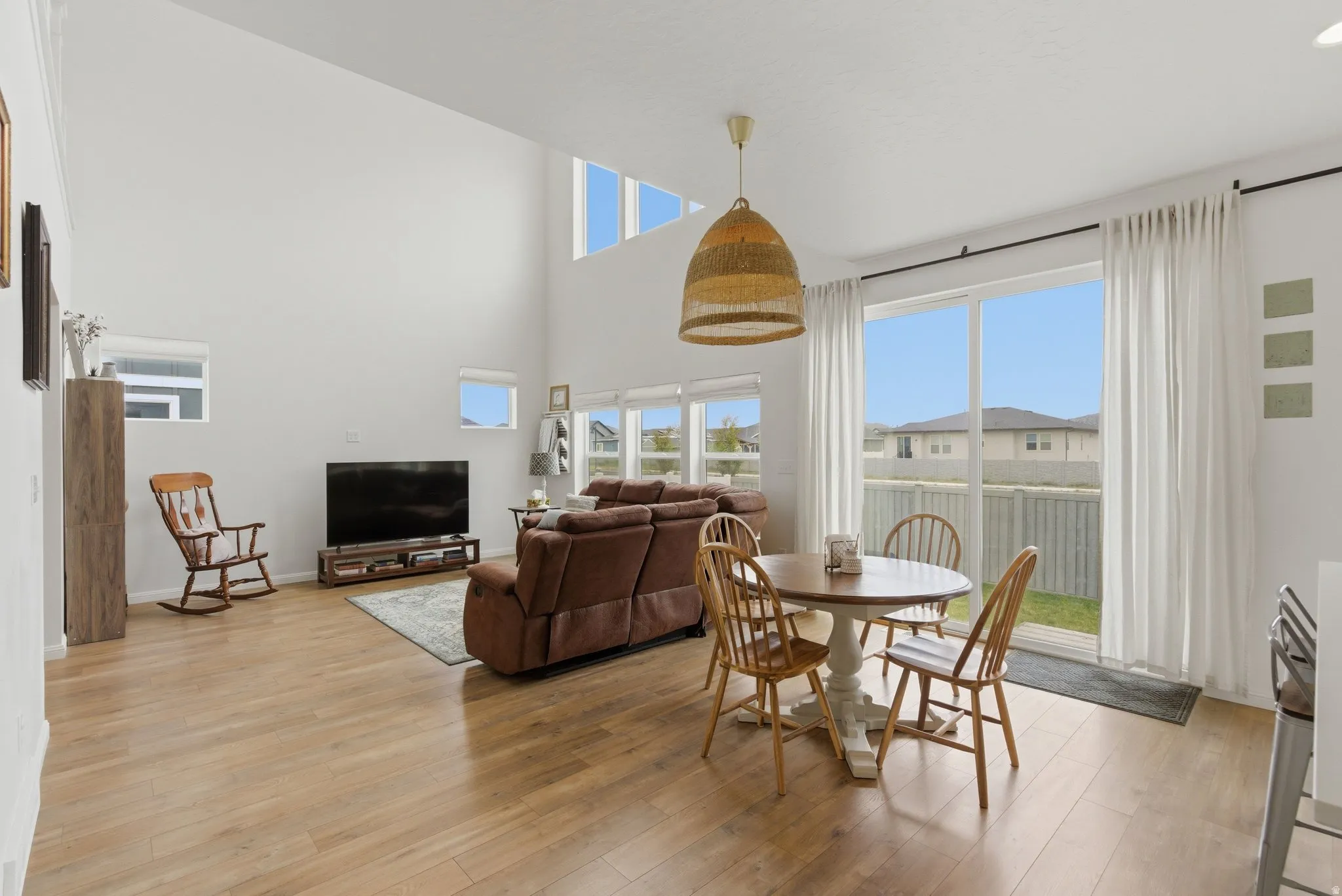 Open-concept living space featuring high ceilings, wood-finish flooring, and multiple windows