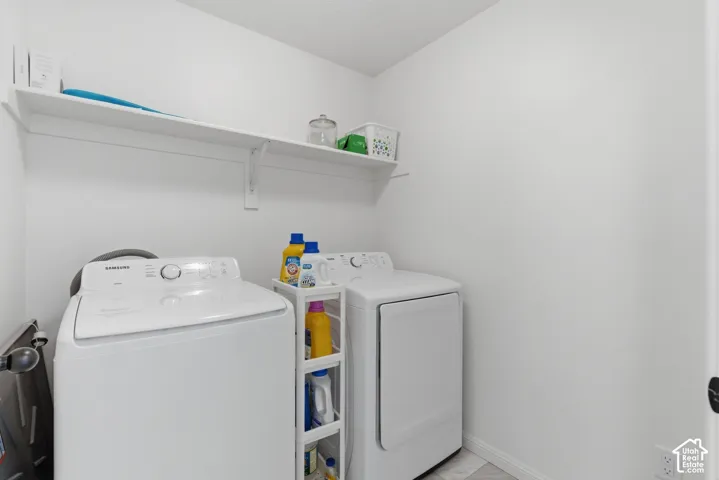 Laundry area featuring a top-load washing machine, front-load dryer, wall-mounted shelving, and light-toned flooring