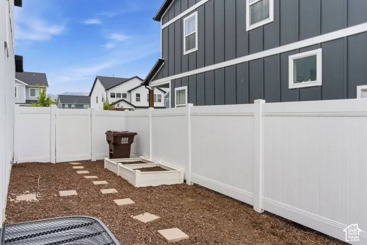 Private fenced yard featuring a stepping stone path and a raised garden bed
