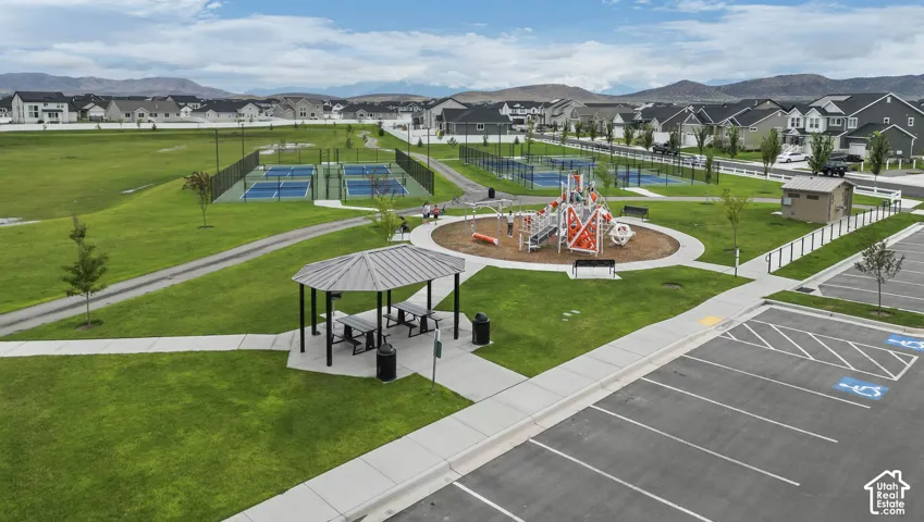 Community park area featuring an expansive playground, multiple tennis courts, a covered picnic gazebo, and paved walking paths