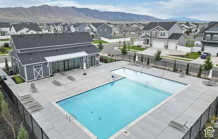 Community pool and amenity building featuring a contemporary gray exterior with white trim, large windows, and an expansive concrete sundeck