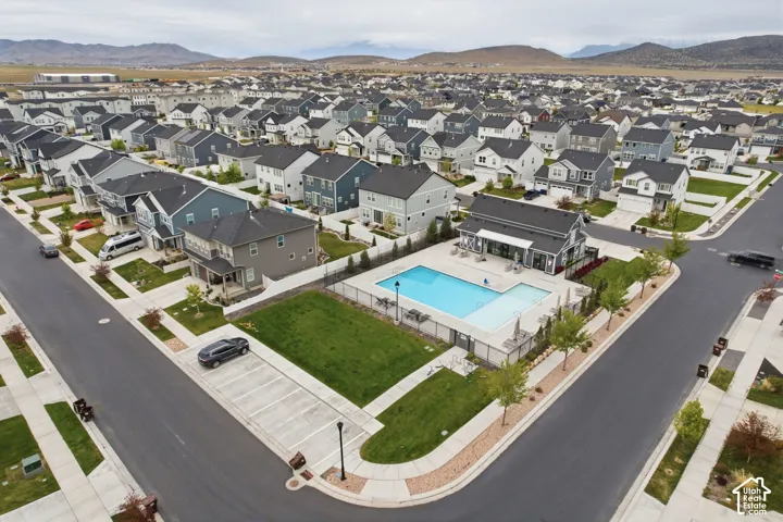 Community swimming pool with surrounding patio, adjacent lawn, and a nearby building