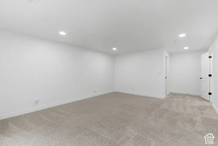 Spacious room featuring neutral carpeting, white walls, recessed ceiling lighting, and white trim