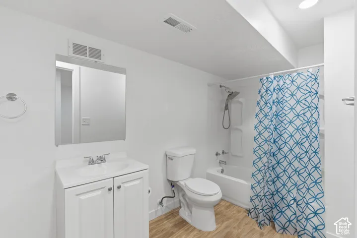 Bathroom featuring a white vanity with cabinet storage, a toilet, and a combined shower-tub unit