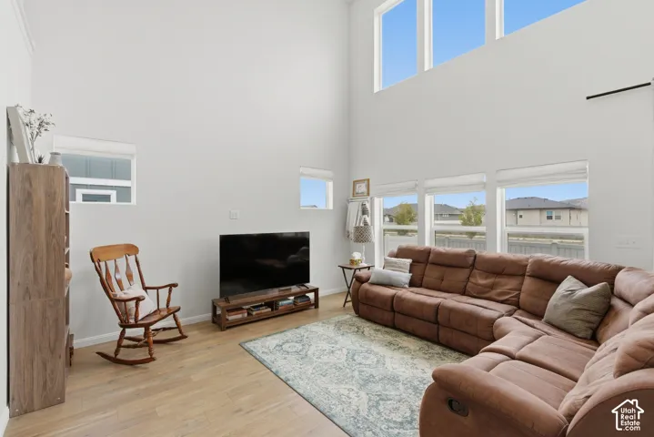 Vaulted ceiling living space featuring high transom windows, wood-finish flooring, and multiple lower windows providing natural light