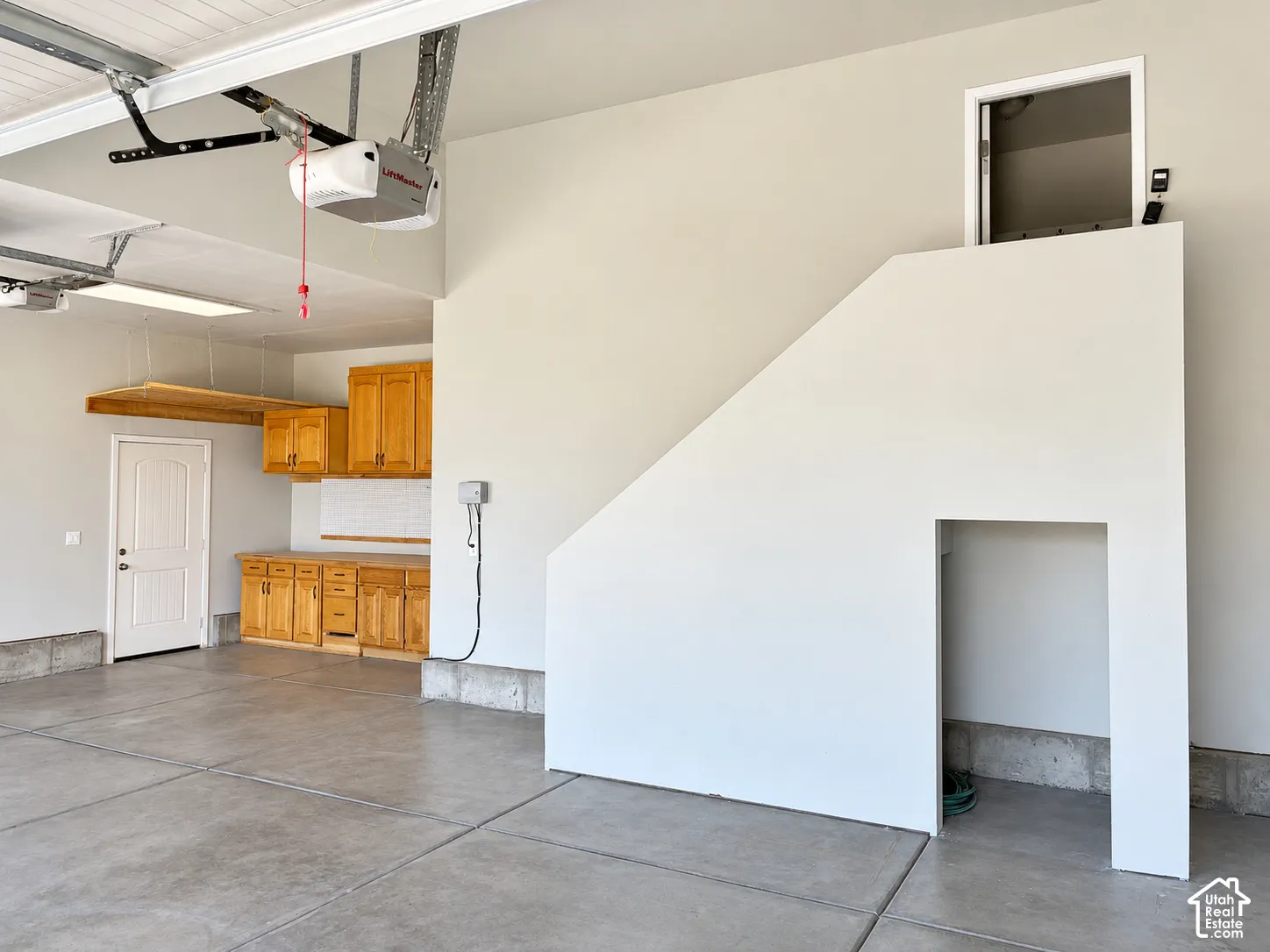Spacious garage featuring a concrete floor, built-in wooden cabinetry, utility sink area, and overhead storage racking
