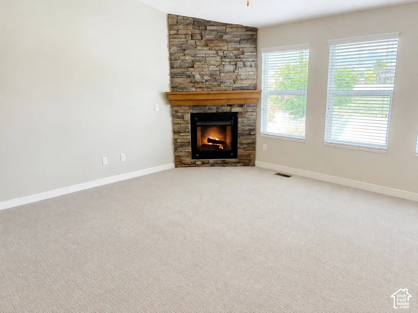 Corner fireplace with a stacked stone surround, wooden mantel, and a built-in firebox