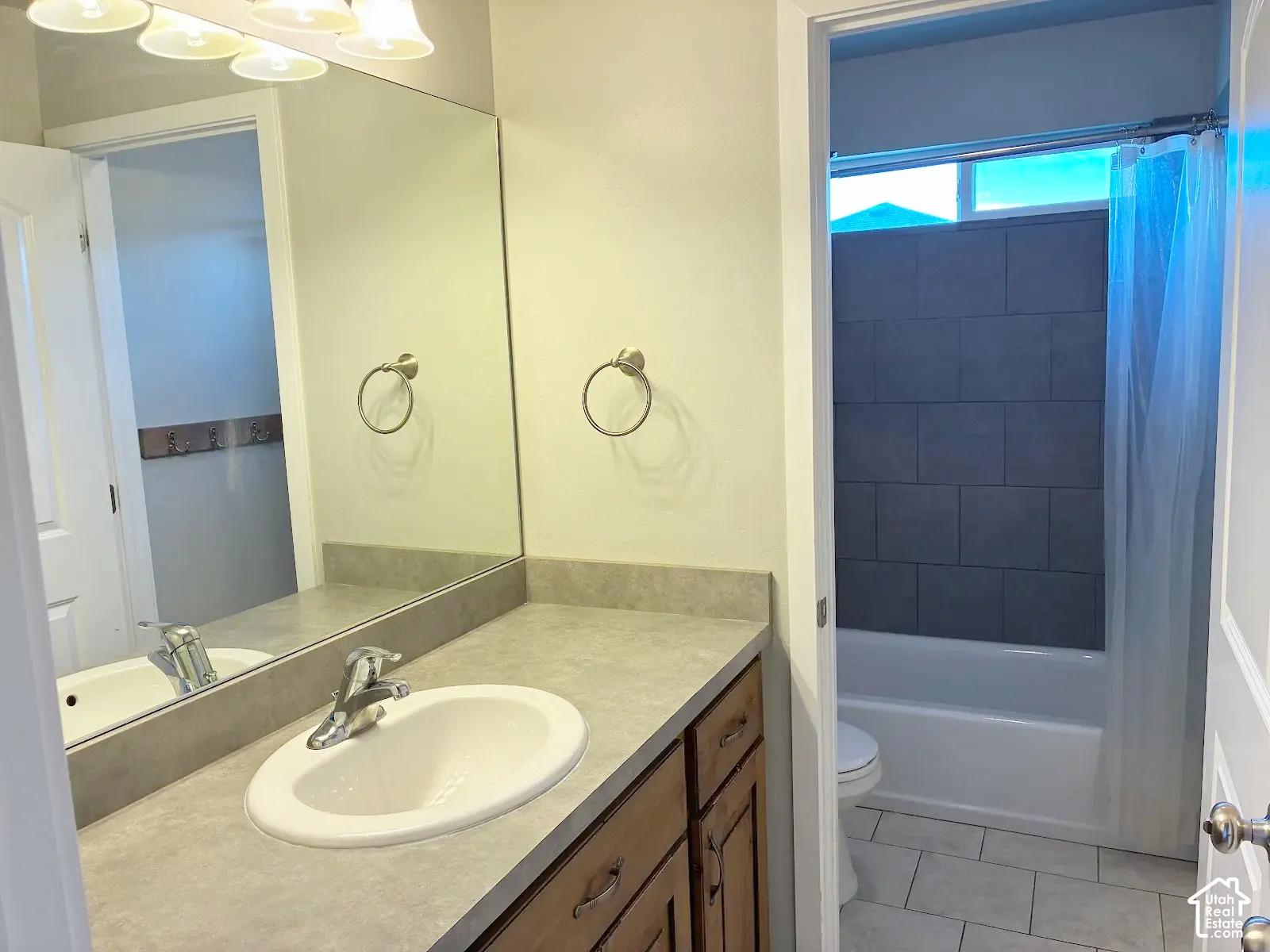 Vanity with an integrated sink and chrome faucet, full-width mirror, and overhead lighting