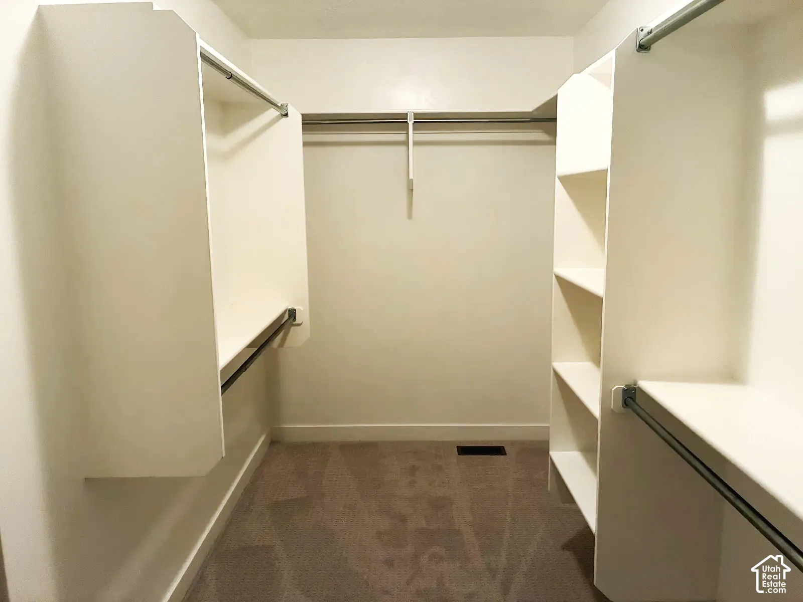 Walk-in closet with carpet flooring, white shelving, and multiple clothing rods