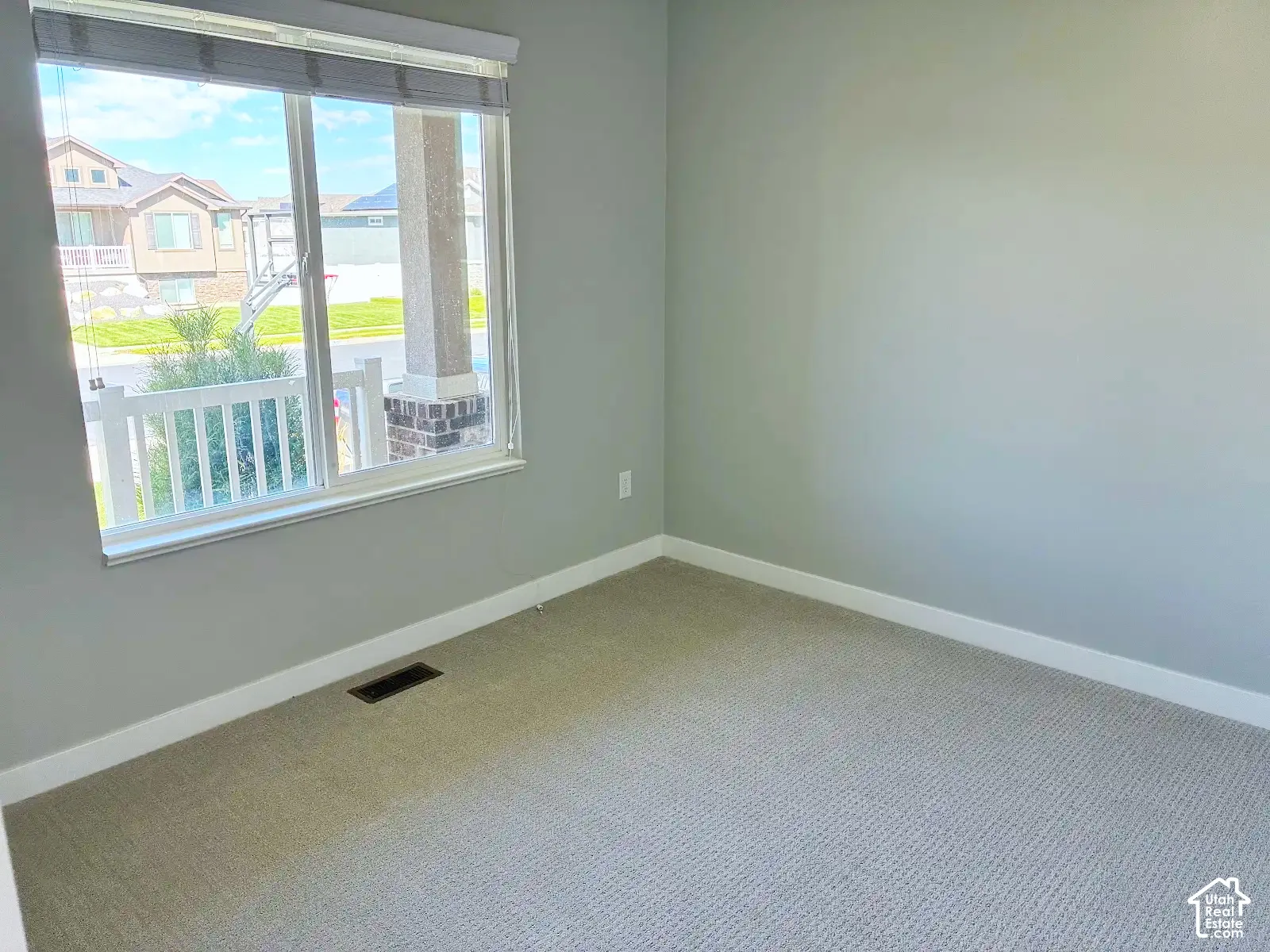 Neutral gray wall paint, light-colored carpet, white trim, and a window with blinds