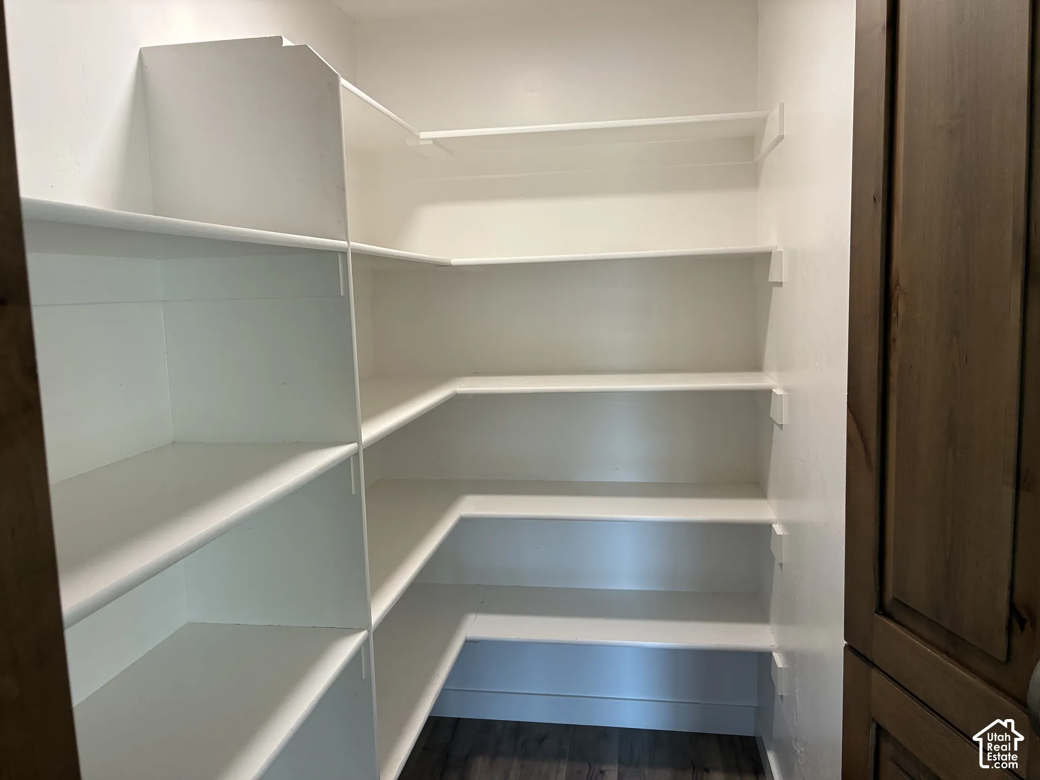 Built-in shelving with multiple levels, white finishes, and wood-finish flooring