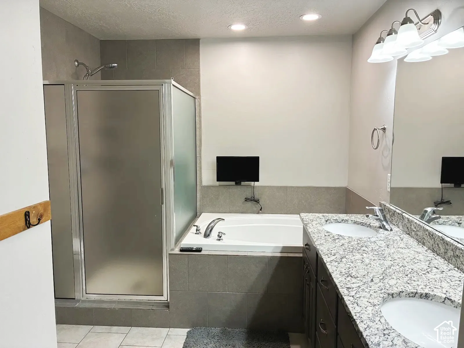 Enclosed shower with frosted glass, large soaking tub, dual vanity with undermount sinks, and granite-look countertop
