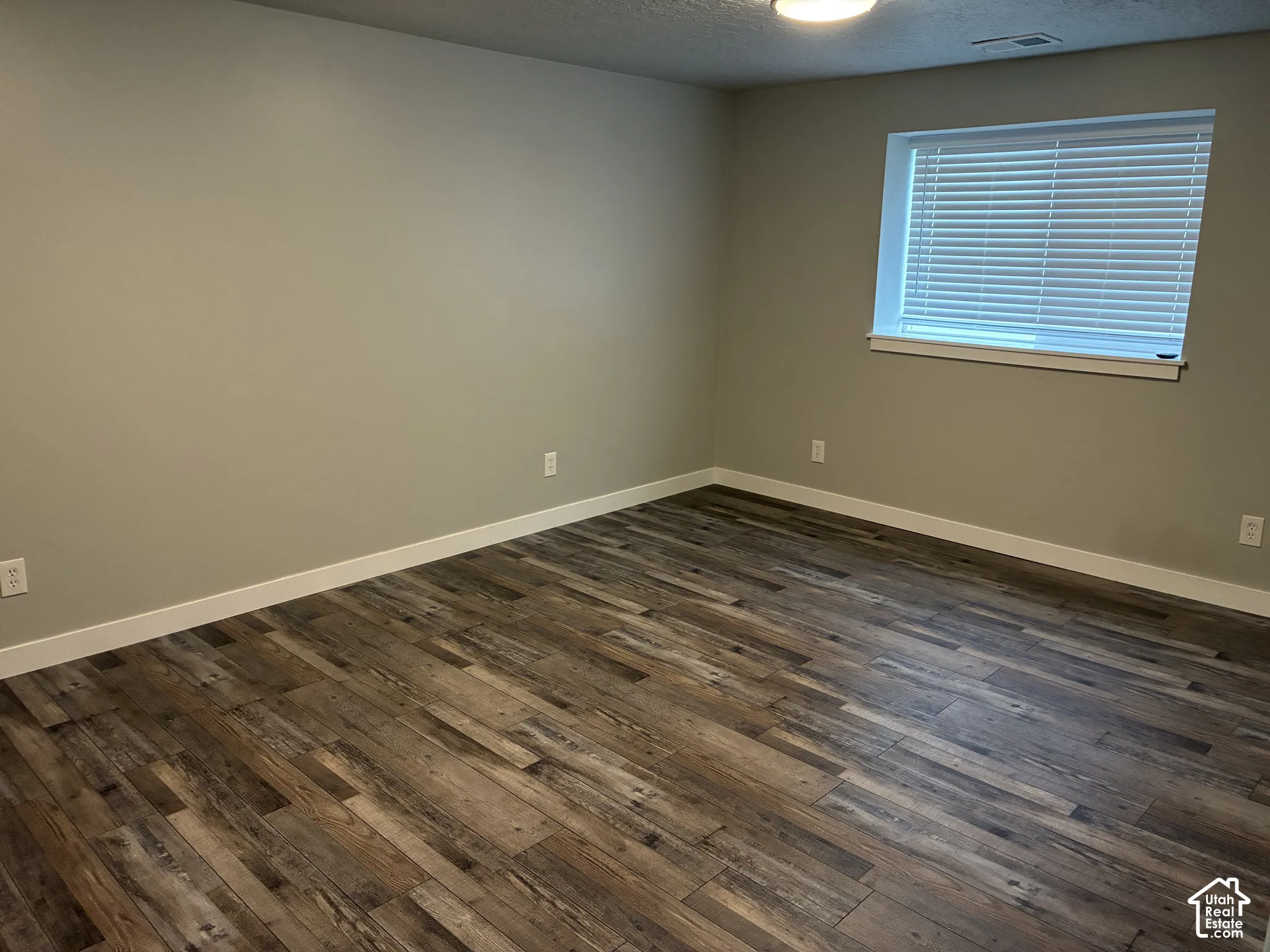Wood-finish flooring, neutral wall tones, white trim, and a window with blinds