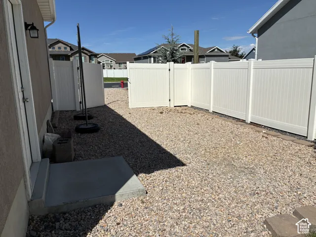 Gravel side yard with a white vinyl fence featuring a gate
