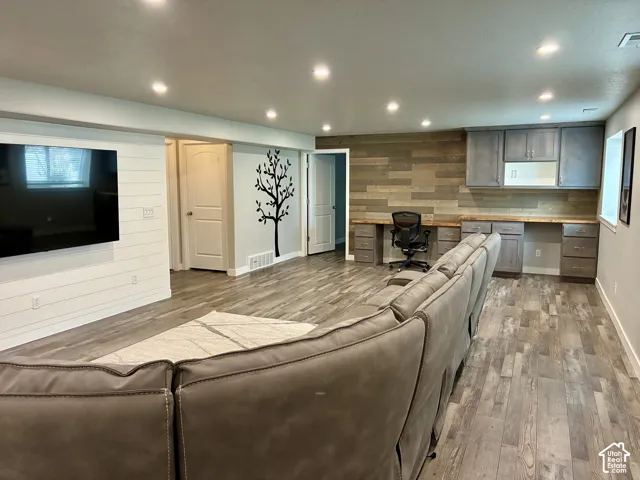 Recessed lighting illuminates the spacious living area, featuring wood-finish flooring and shiplap accent wall
