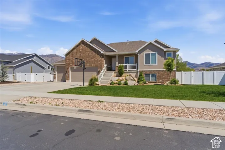 Stucco and brick exterior with a multi-car garage, concrete driveway, and tiered landscaping