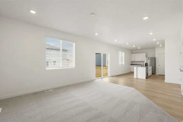 Open concept living area with recessed lighting, light gray carpeting, and wood-finish flooring