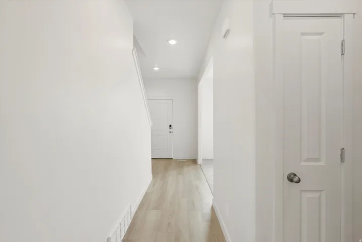 Entryway featuring light wood-finish flooring, recessed ceiling lighting, a paneled interior door with a brushed nickel knob, and a white baseboard trim
