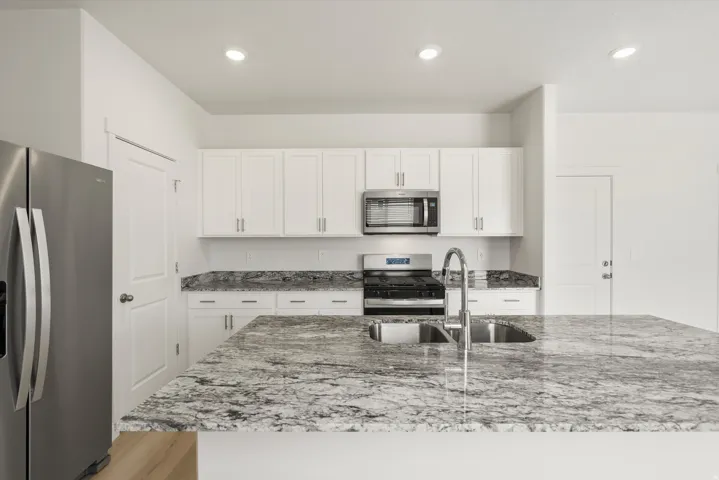 Kitchen featuring a stainless steel appliance suite, white shaker cabinetry, granite countertops, and recessed lighting