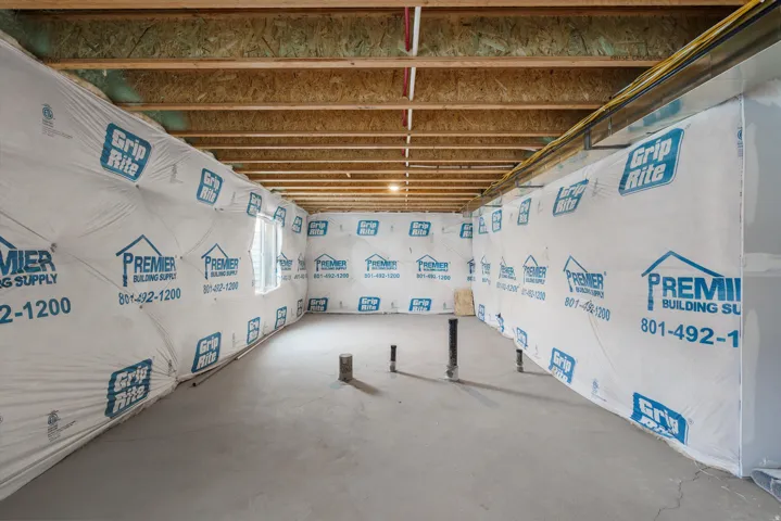 Unfinished basement space featuring exposed wood joists and concrete flooring