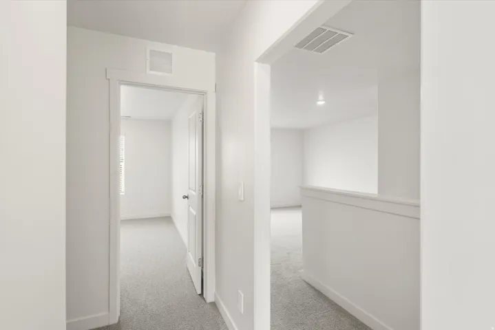 Hallway featuring light gray carpeting, white walls, and white trim