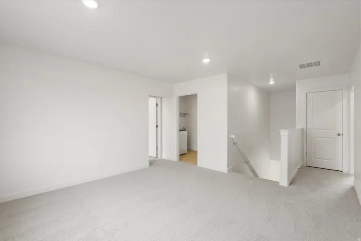 Carpeted landing area featuring recessed lighting, white walls, and a white stair railing