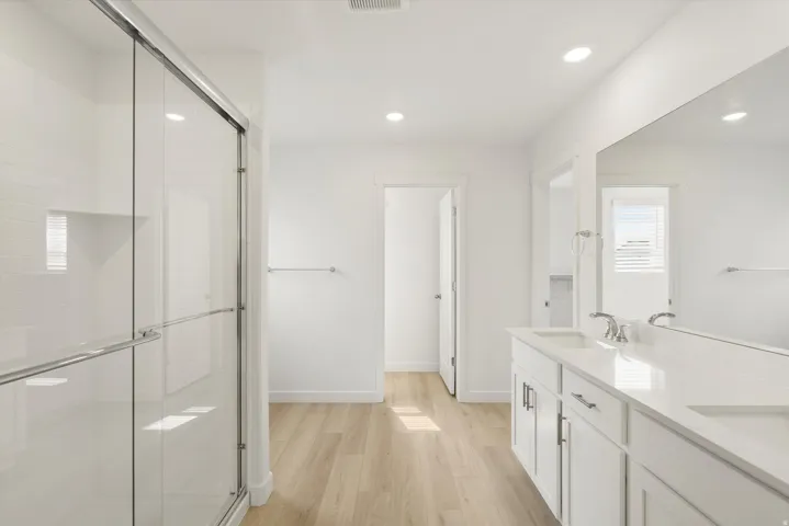 Contemporary bathroom featuring a dual vanity with white cabinetry, integrated sinks, and polished chrome fixtures