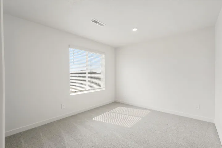 Room featuring light gray carpeting, crisp white walls, a single window with horizontal blinds, and a recessed ceiling light