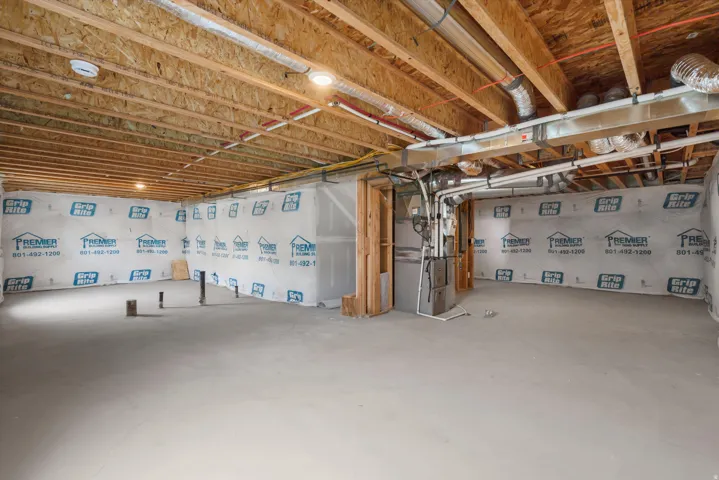 Unfinished lower level featuring exposed wood joists, concrete flooring, perimeter framing, and visible utility runs