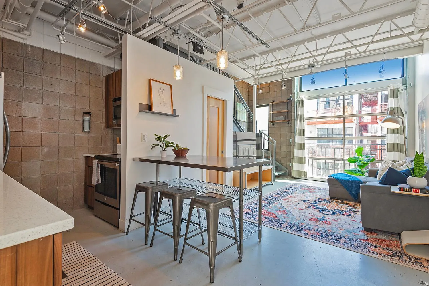 Loft-style residence featuring an open-concept layout with concrete-block accent walls and exposed ceiling infrastructure