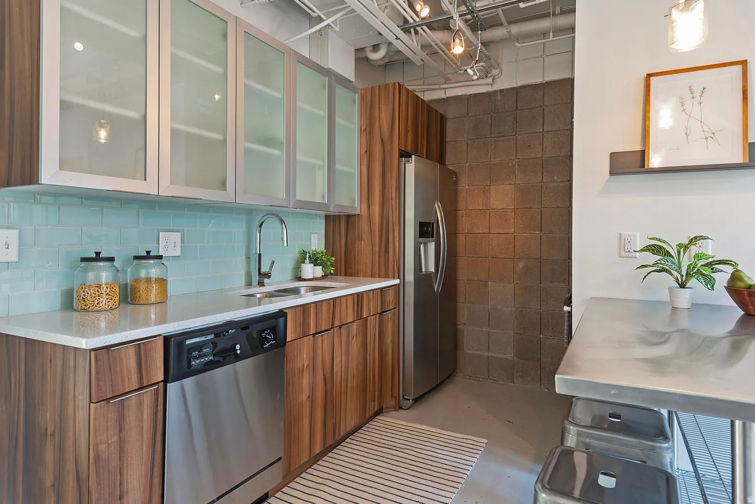 Modern kitchen featuring wood-finish cabinetry, stainless steel appliances, and a light blue subway tile backsplash