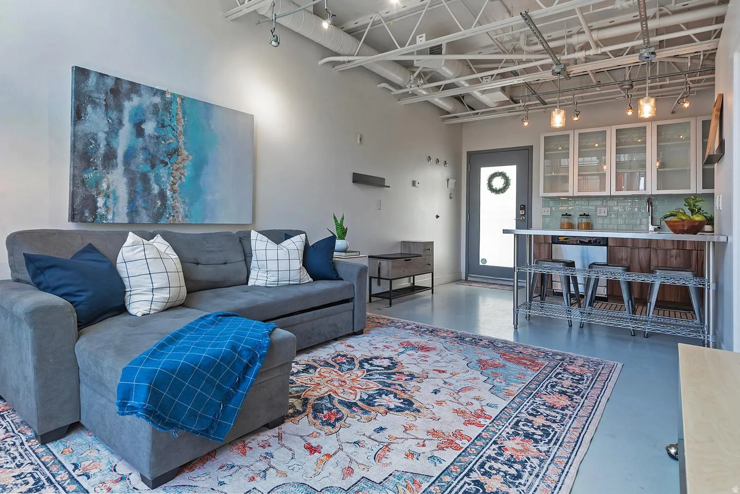 Open-concept living area featuring high exposed ceilings and track lighting
