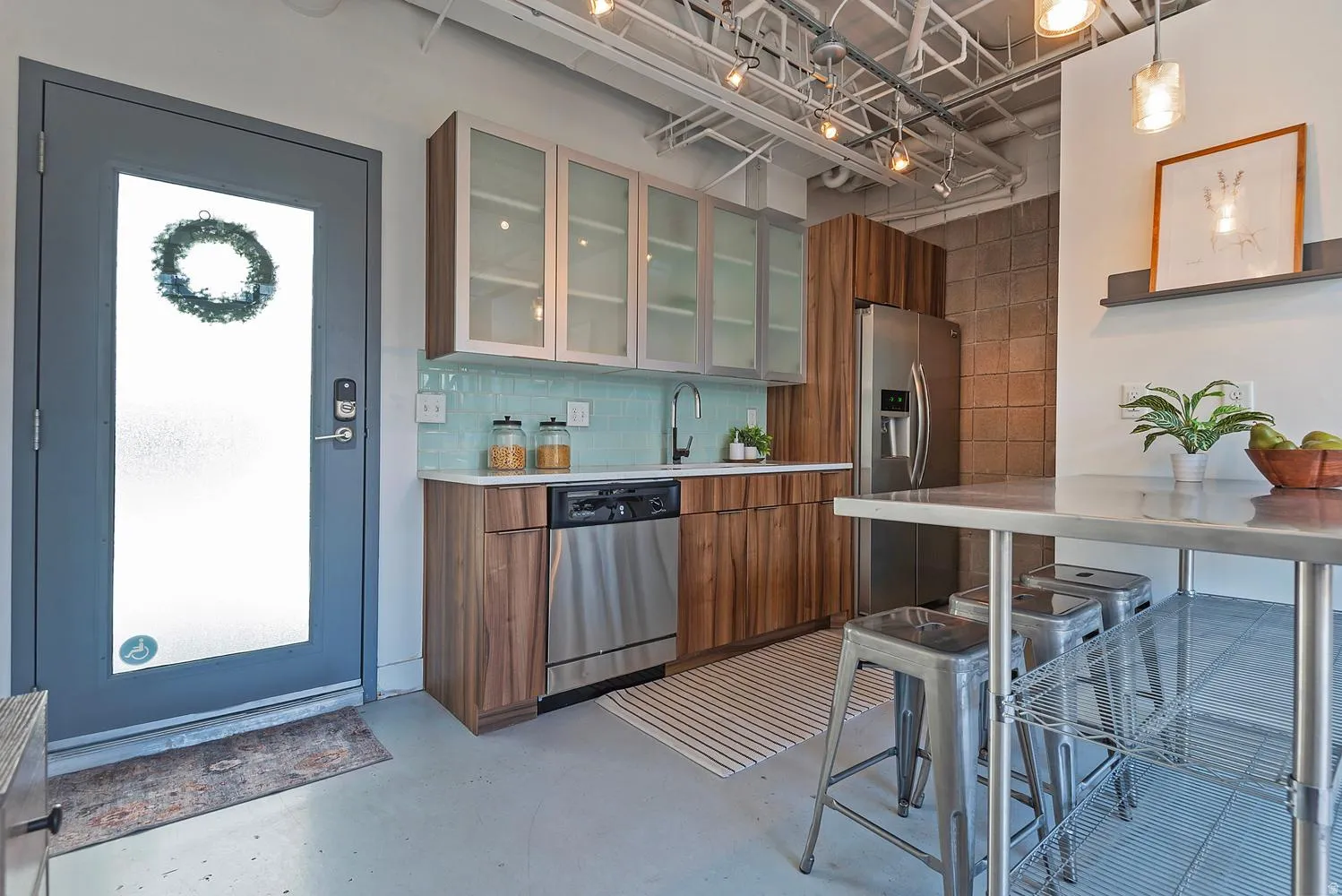 Modern kitchen featuring wood-finish lower cabinetry, stainless steel appliances, and a light blue tile backsplash