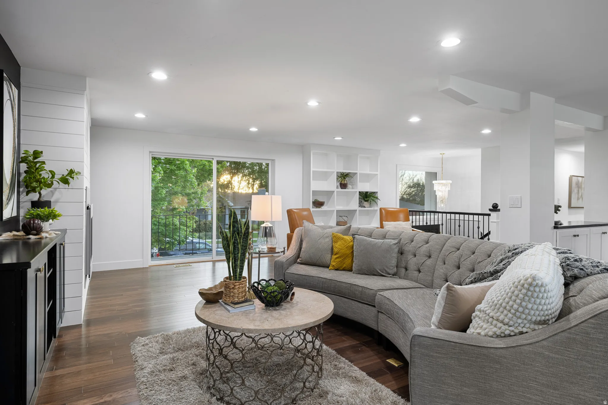 Spacious living area featuring wood-finish flooring, recessed lighting, and a sliding glass door to an outdoor balcony