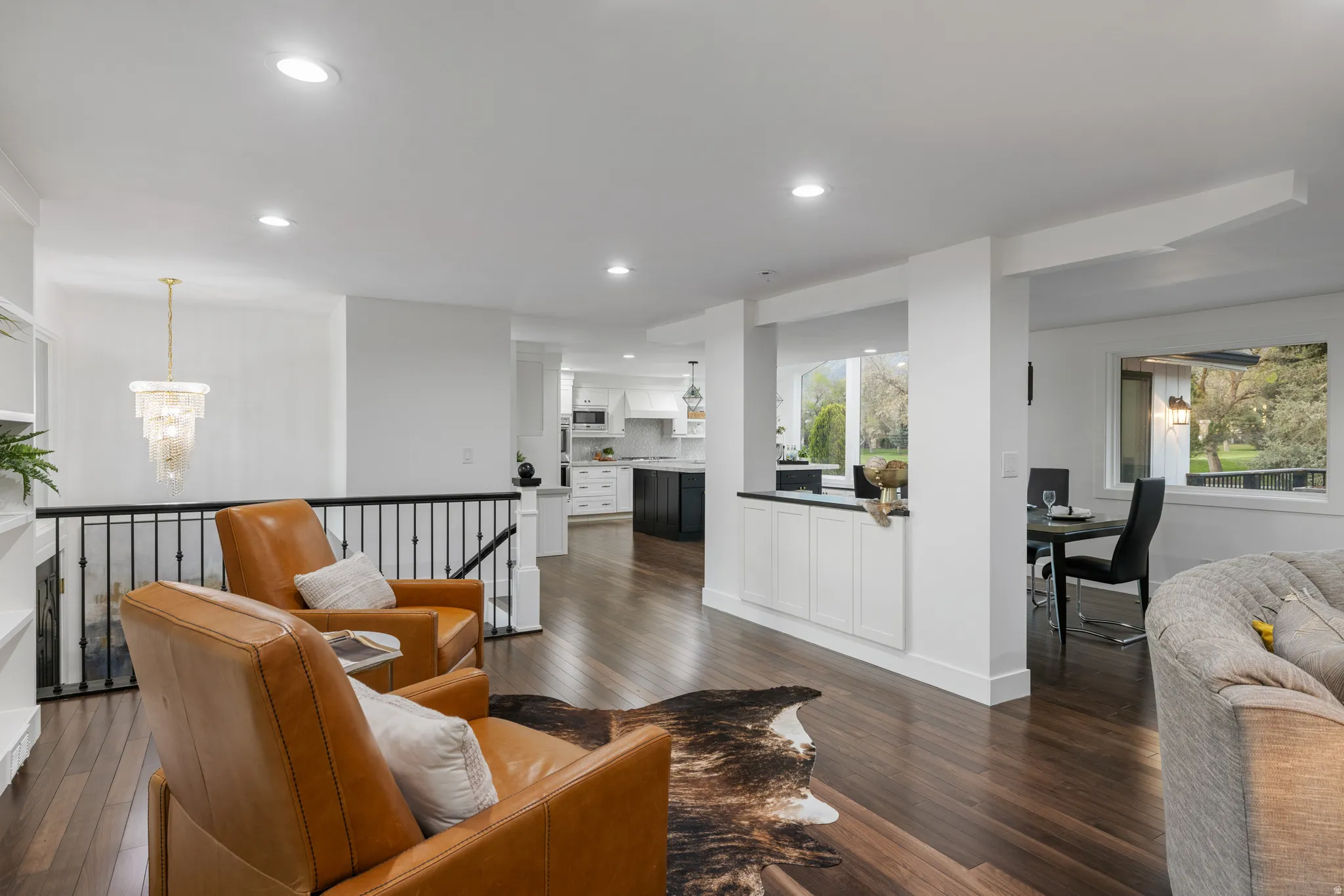 Open-concept living area featuring wood-finish flooring, recessed lighting, and a tiered chandelier