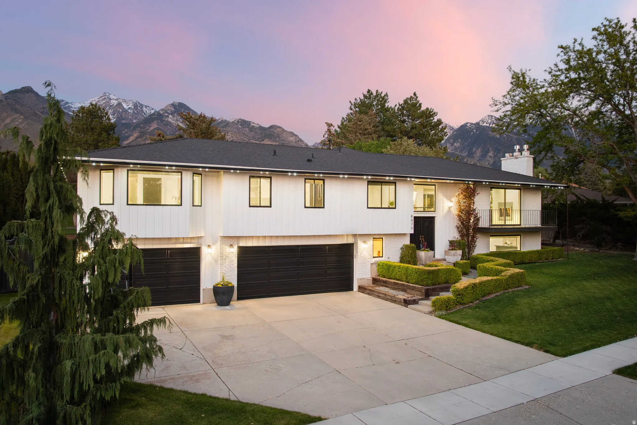 Contemporary split-level residence featuring a dark asphalt shingle roof, white siding, and black-framed windows