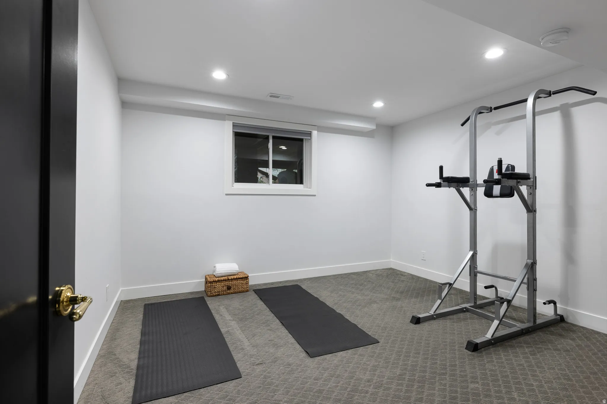 Versatile room featuring light grey walls, recessed ceiling lighting, a single window, and textured grey carpeting